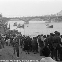 17. La orilla derecha del Guadalquivir se convierte en un graderío de espectadores que siguen las competiciones ante la atenta mirada de la autoridad. 1965. © ICAS-SAHP, Fototeca Municipal, archivo Serrano. 