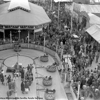 Feria de 1942. Atracciones, barracas y tenderetes en la “calle del infierno”. El látigo, los coches de choque, la barraca La Carcajada y las tómbolas reúnen a personas de toda clase o condición.