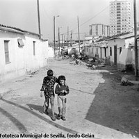 12. Barriada de La Dársena, 1977. Fue derribada en 1977 tras haber sufrido un fuerte temporal que asoló la mayoría de las precarias viviendas. Esta inestabilidad y la especulación inmobiliaria hicieron que los vecinos tuvieran que abandonar sus viviendas para ser trasladados a las nuevas construcciones en el Polígono Sur.   ©ICAS-SAHP. Fototeca Municipal de Sevilla, fondo Gelán