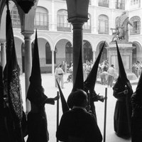 Formación de los tramos de nazarenos en el patio de la antigua Universidad. Al fondo, bajo la escultura de Maese Rodrigo, preparativos de las cuadrillas de costaleros profesionales. 1955 ©ICAS-SAHP, Fototeca Municipal de Sevilla, fondo Serrano