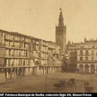 La actual plaza de San Francisco, rotulada entonces como Isabel II, aparece muy distinta a la imagen actual. A la derecha, la Pila del Pato, que había sustituido a la fuente de Mercurio de Morell en 1850 y el caserón de la llamada Lonja de los Genoveses. Al frente aún persiste la línea de casas con soportales. [1853-1858]. ©ICAS-SAHP, Fototeca Municipal de Sevilla, colección Siglo XIX, Bisson Fréres