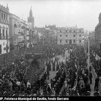 Palcos en la plaza de San Francisco para contemplar el paso de las cofradías. El palio de la Virgen de la Esperanza de la Hermandad de la Trinidad transita por delante del edificio consistorial. La nueva fachada de la Audiencia Provincial aparece ya pintada en blanco, abandonando el característico color rojizo ideado en 1926 por Aníbal González. 1930  ©ICAS-SAHP, Fototeca Municipal de Sevilla, fondo Serrano 