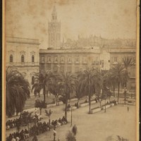 Tomada desde la fonda Peninsular, esta vista nos muestra el rígido perímetro rectangular de la plaza en el ángulo sureste (Casas Consistoriales y manzanas de viviendas separadas por la desaparecida calle Numancia). En la plaza, muy concurrida, se observan las farolas artísticas de la Fundición San Antonio de Pérez Hermanos S.A. ca.1890. ©ICAS-SAHP, Fototeca Municipal de Sevilla, fondo Larrazábal