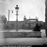 Vista a pie de plaza con las Casas Consistoriales al fondo. En el centro, quiosco para espectáculos al aire libre. En primer plano, hombre sentado en uno de los bancos con respaldo de hierro. 1893. ©ICAS-SAHP, Fototeca Municipal de Sevilla, fondo Caparró