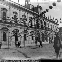 Andén del Ayuntamiento decorado con farolillos por la festividad del Corpus Christi. En la fachada se observa el templete metálico con la campana del reloj que se eliminó en las reformas de las primeras décadas del siglo XX. 1985. ©ICAS-SAHP, Fototeca Municipal de Sevilla, fondo Caparró