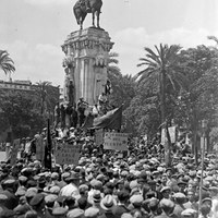 Celebración del Primero de Mayo, Fiesta del Trabajo. Manifestación comunista en la Plaza Nueva. En las pancartas se pueden leer consignas tales como "Derecho político a los 18 años" y "Obreros del puerto", entre otras. En el monumento a San Fernando ondea la bandera republicana, colocada el 15 de abril tras la proclamación de la II República. 1 de mayo de 1931. ©ICAS-SAHP, Fototeca Municipal de Sevilla, fondo Sánchez del Pando