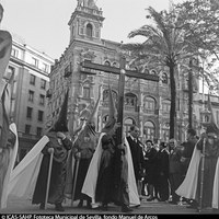 Nazarenos portando la Cruz de guía de la Hermandad de las Cigarreras. Detrás, el edificio de la Compañía Telefónica. 1963. ©ICAS-SAHP, Fototeca Municipal de Sevilla, fondo Manuel de Arcos